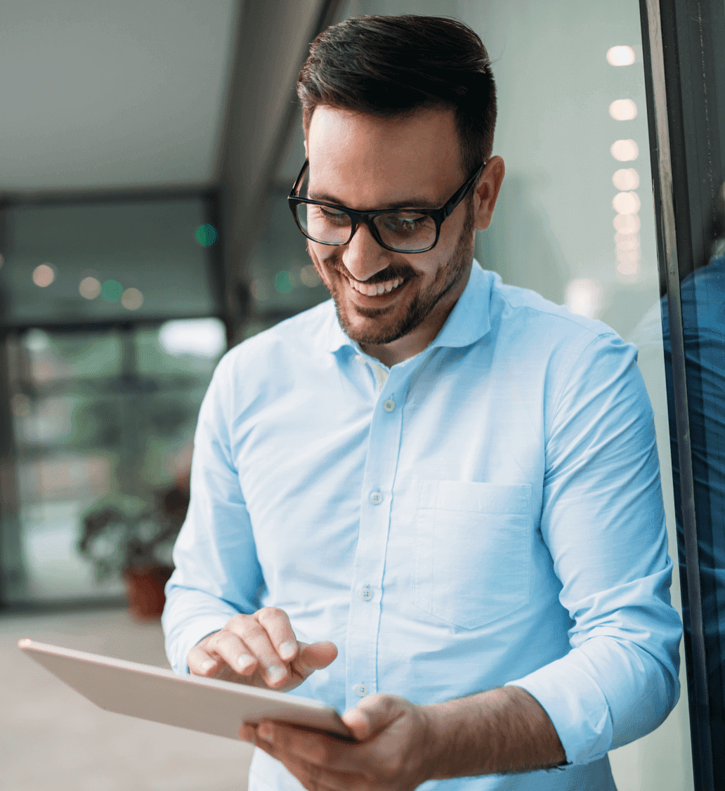 A man with glasses happily using a tablet device.